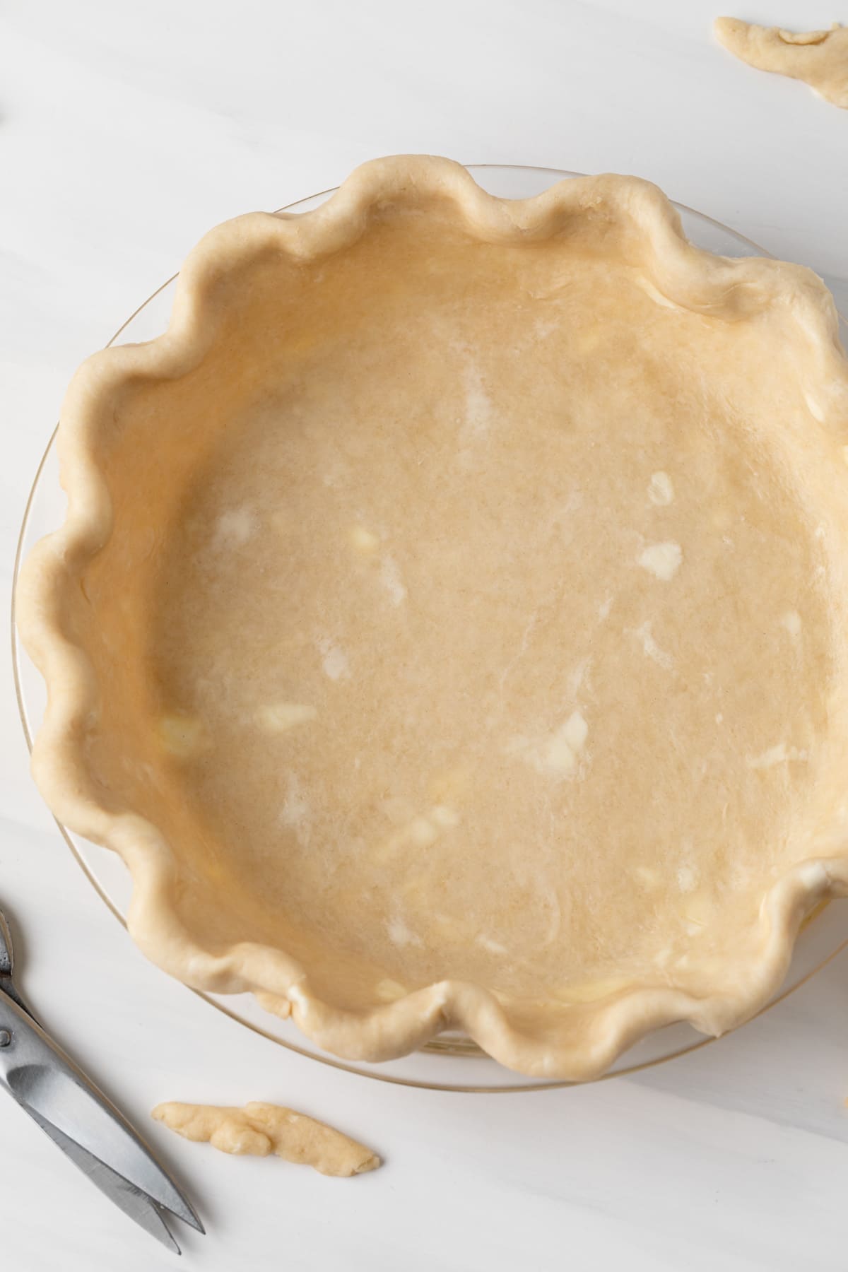 overhead of unbaked pie crust in glass pie pan