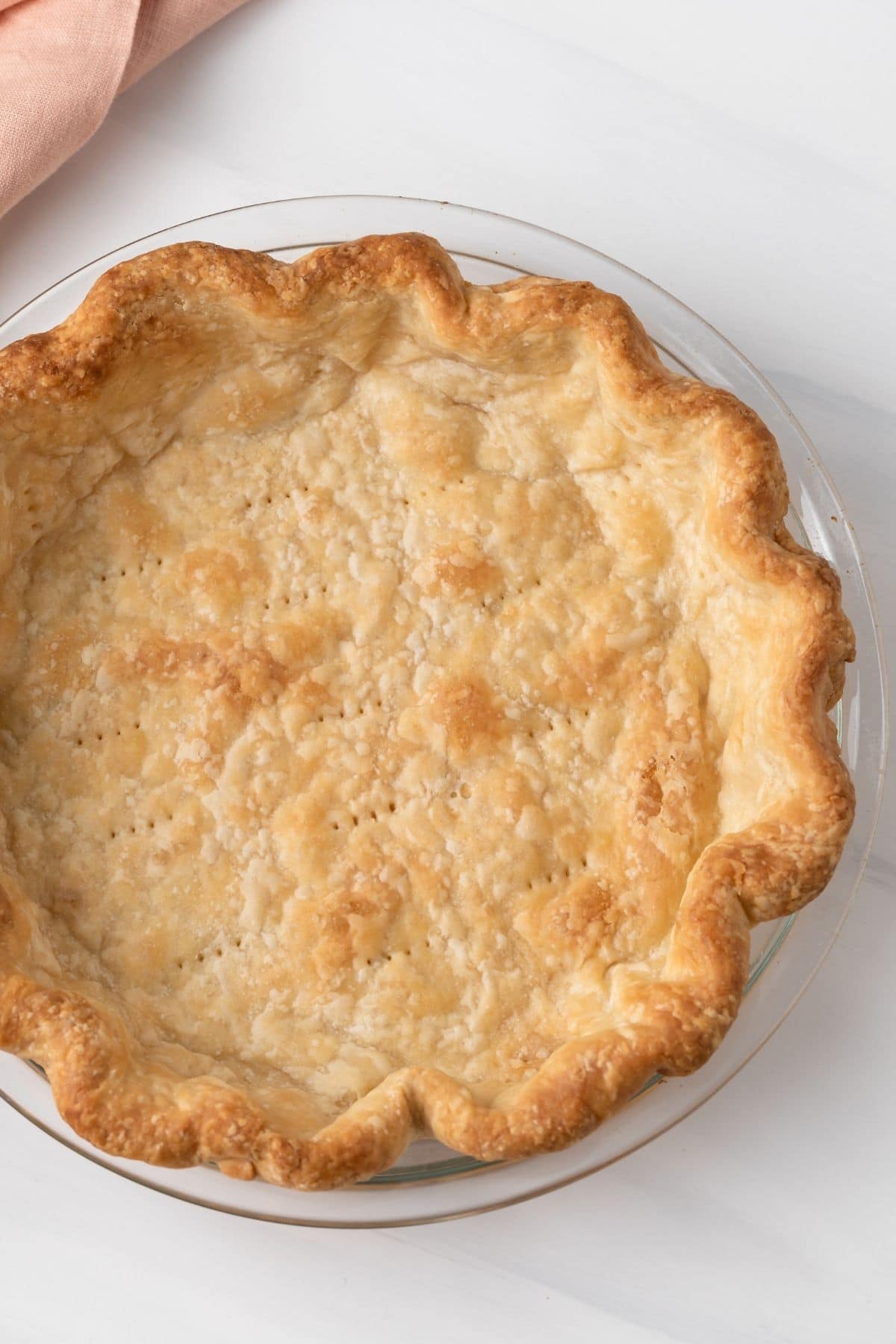close up of blind baked pie crust in glass pan