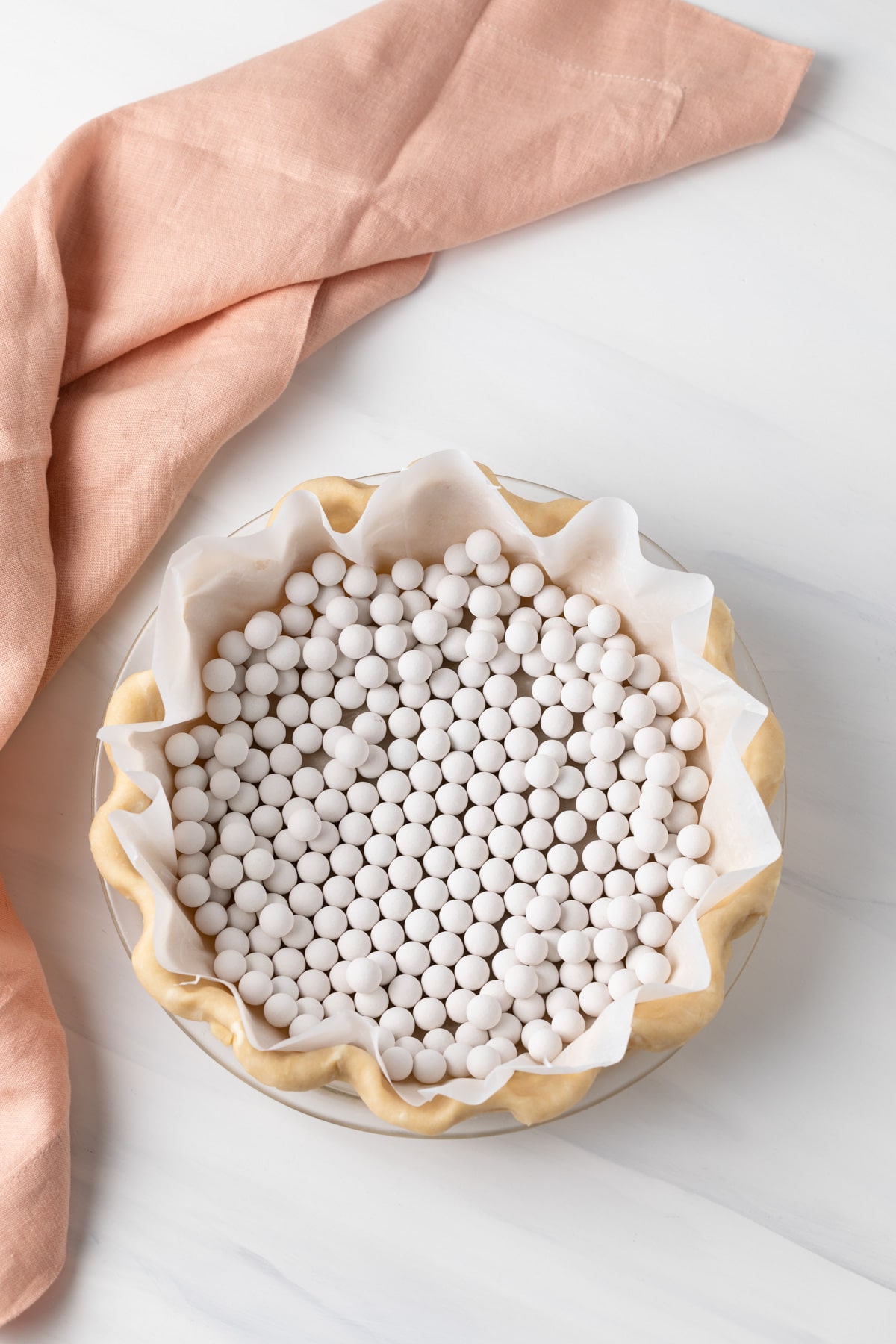 overhead of unbaked pie shell lined with parchment paper and filled with pie weights