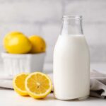 glass jar filled with homemade buttermilk along with a napkin and lemons in the background