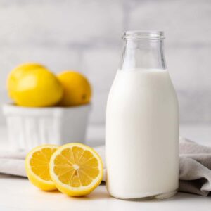 glass jar filled with homemade buttermilk along with a napkin and lemons in the background