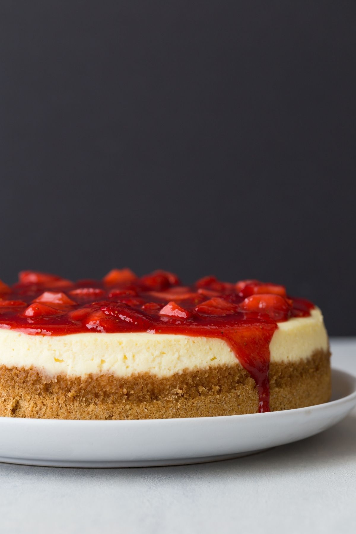 cheesecake topped with strawberry sauce on white plate