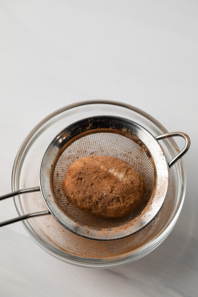 Cinnamon coated potato candy in sieve.