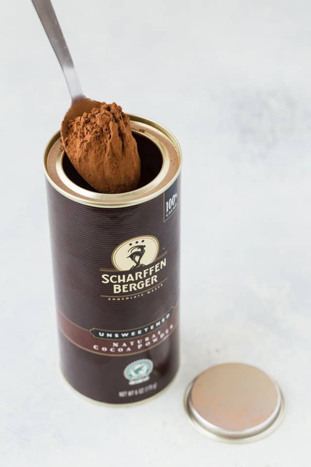 A jar of cocoa powder with a spoon getting some out.