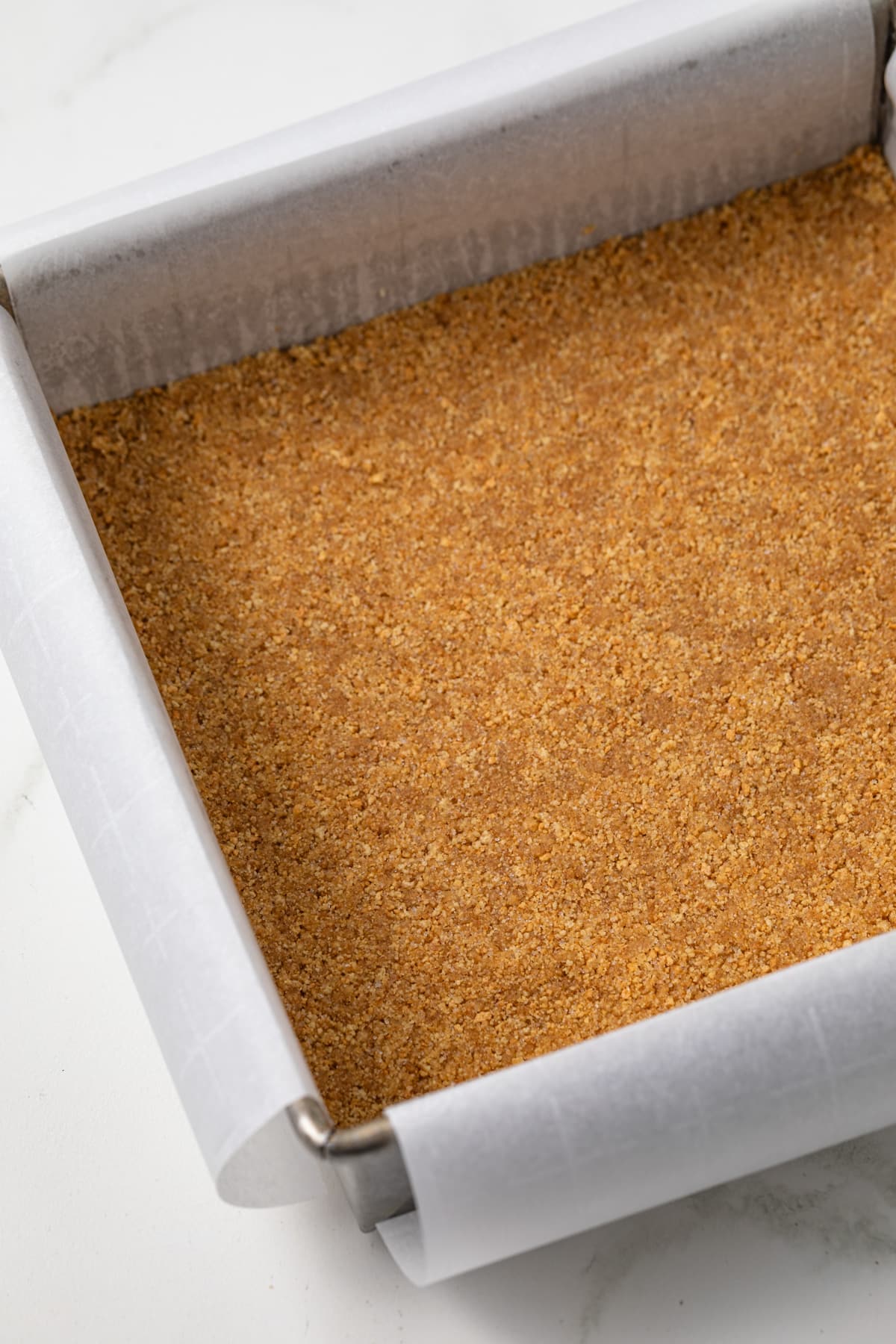 Graham cracker crust in a square pan.