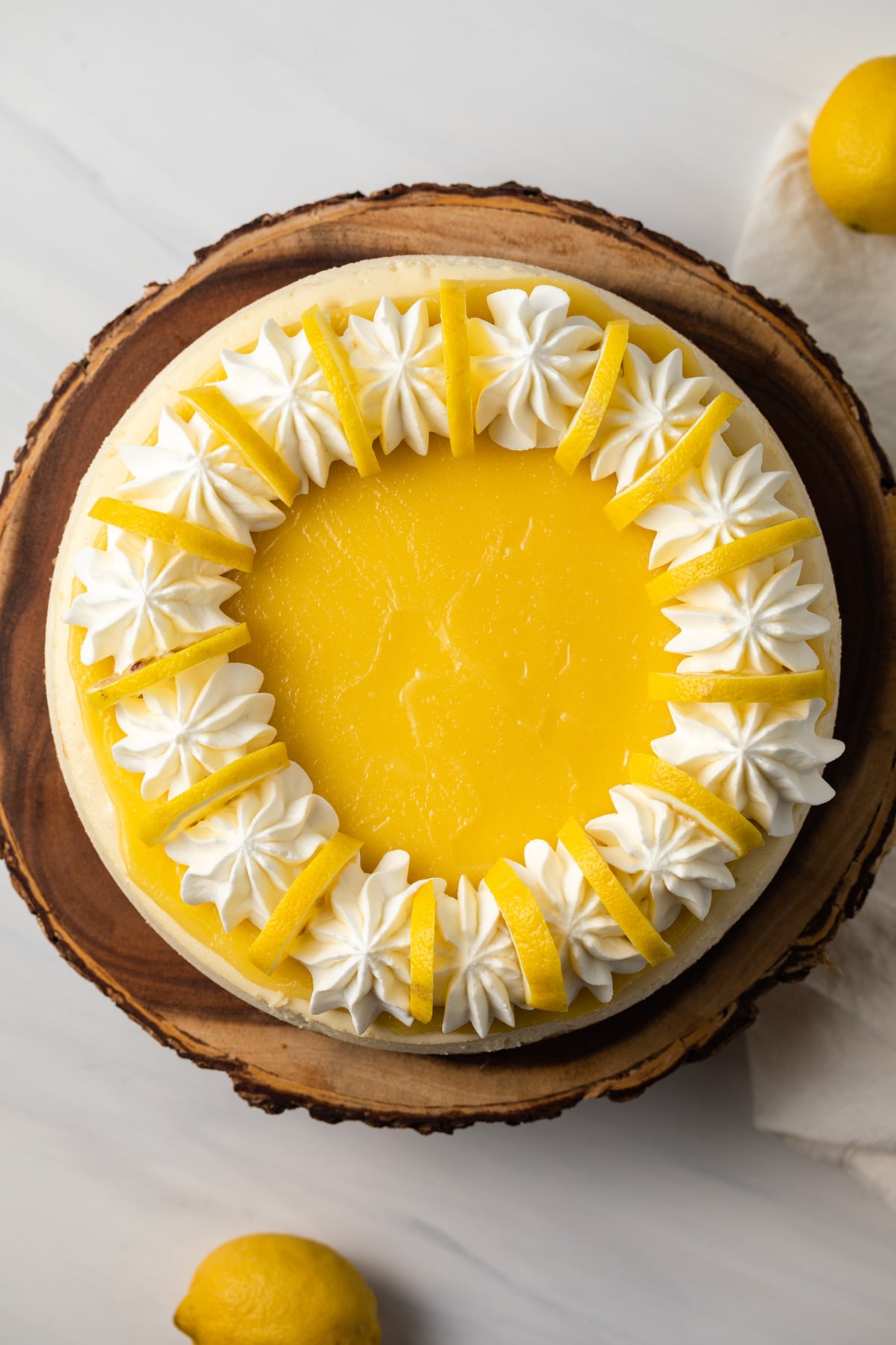 Overhead of lemon cheesecake on wooden stand.