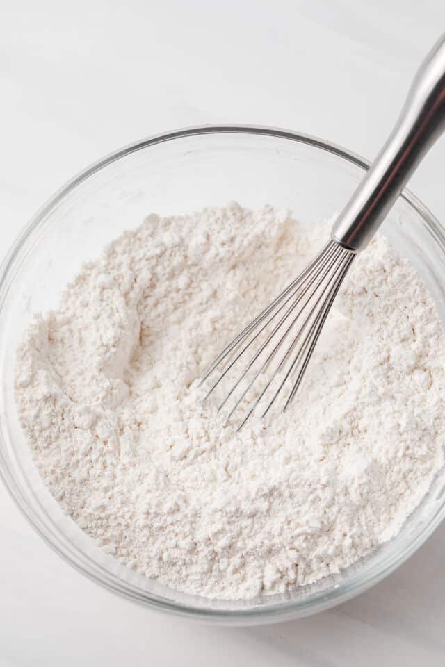 Dry ingredients mixed in glass bowl with whisk.