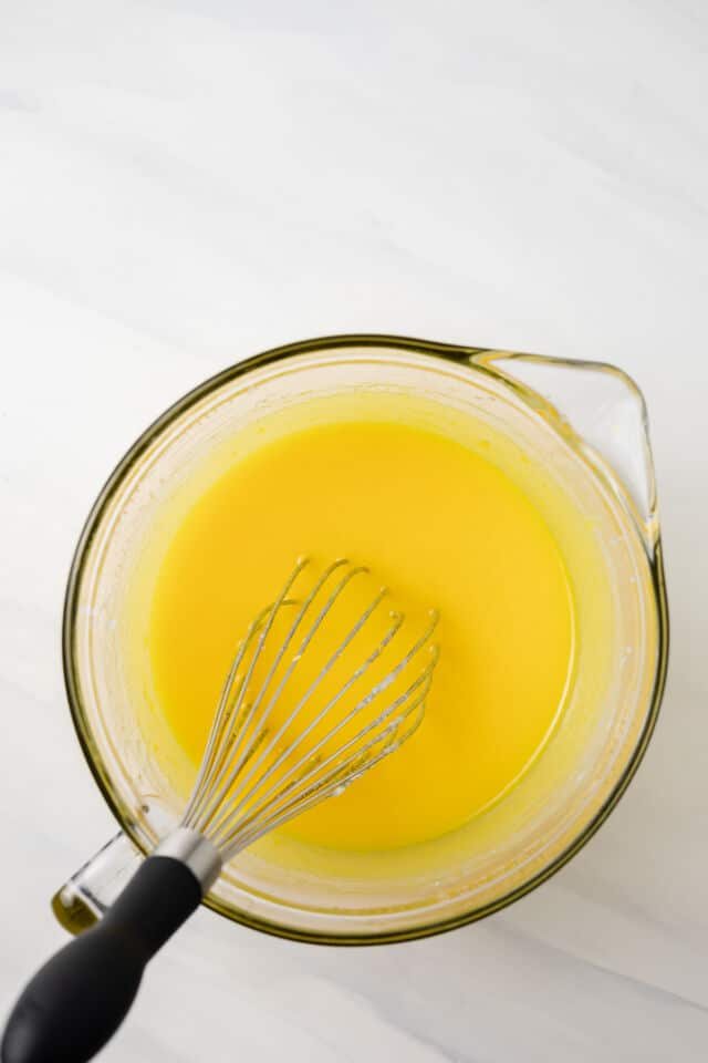 Wet ingredients mixed in glass bowl with whisk.