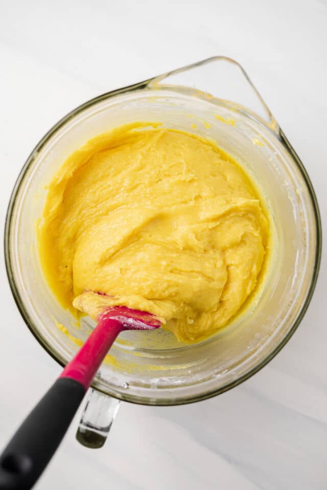 Lemon cookie batter in glass bowl with silicone spatula.