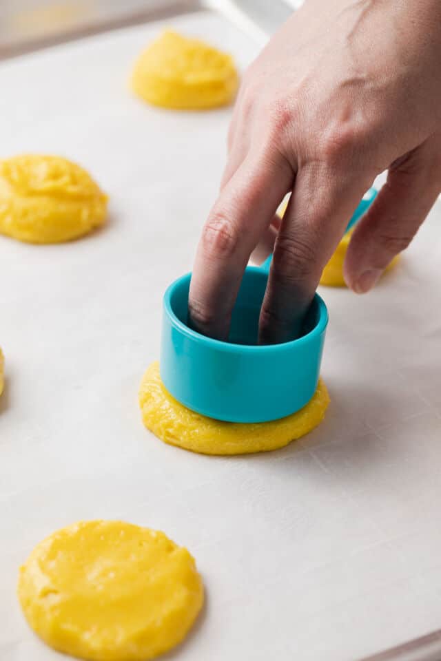 Pressing cookie dough flat with measuring cup.