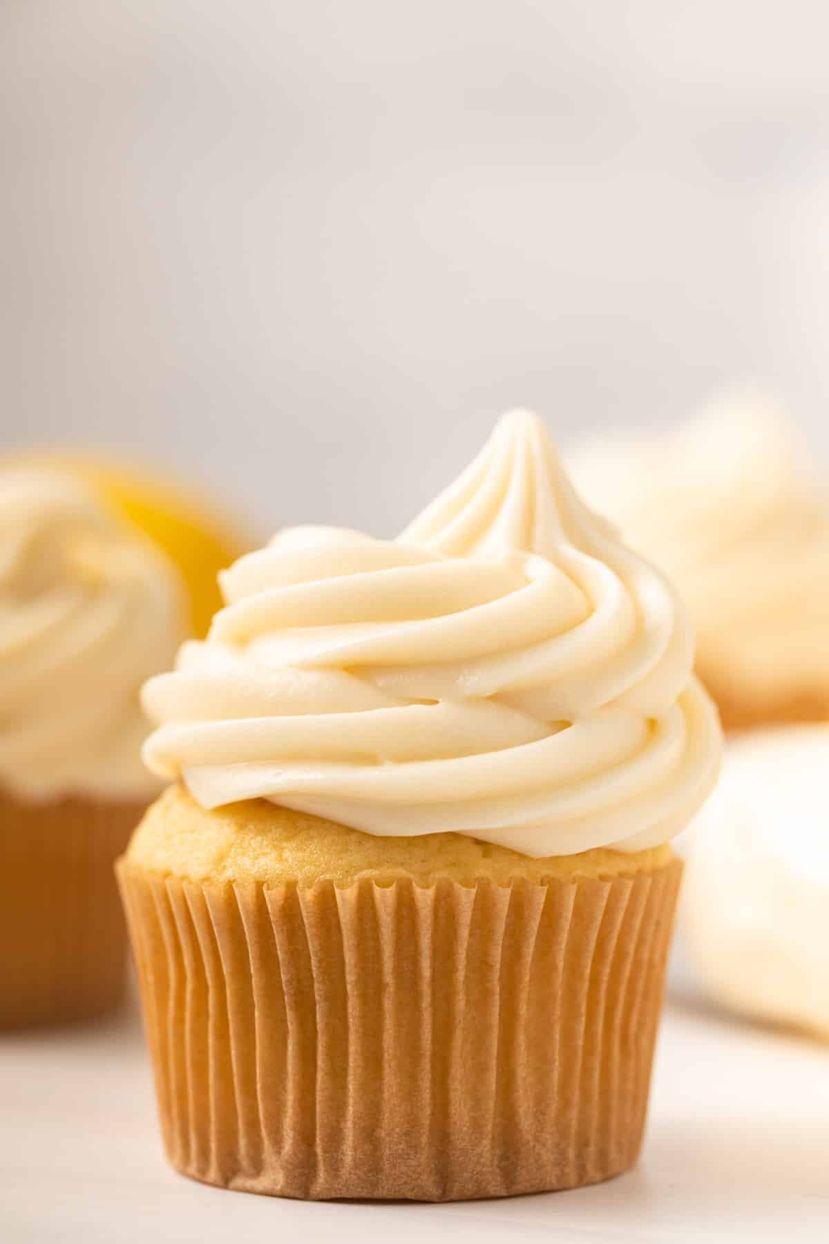 Close up of lemon cream cheese frosting swirled in top of a cupcake.