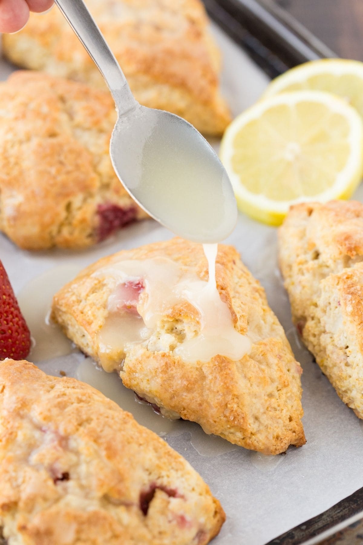 Lemon glaze being drizzled over a lemon cream cheese scone.