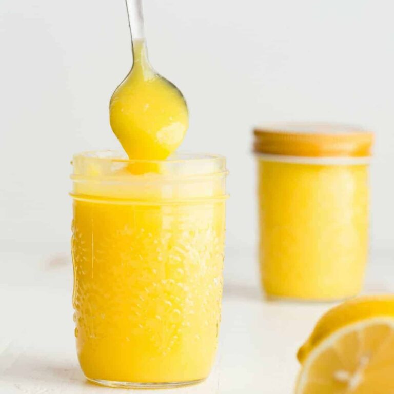 Lemon curd being spooned out of a jar.