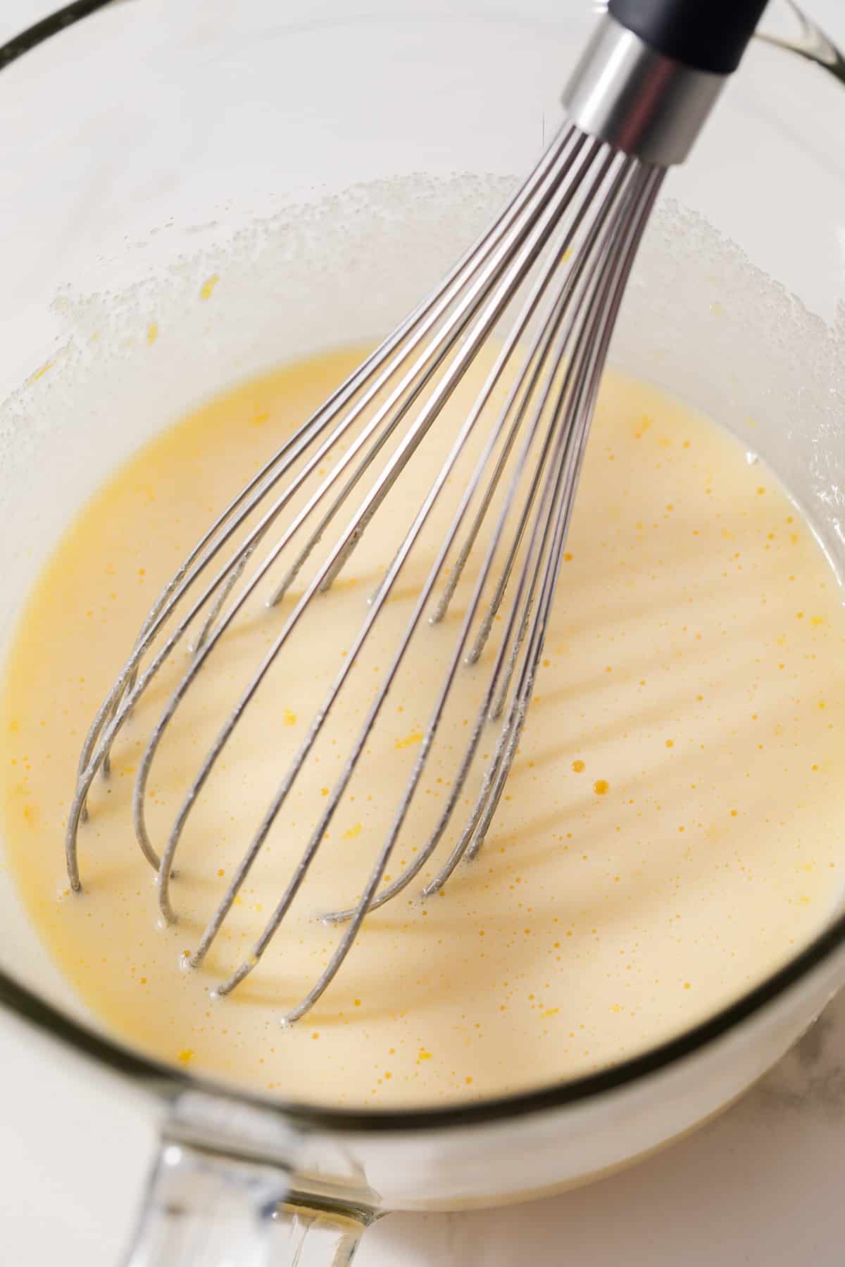 Eggs and sugar mixed in glass bowl.