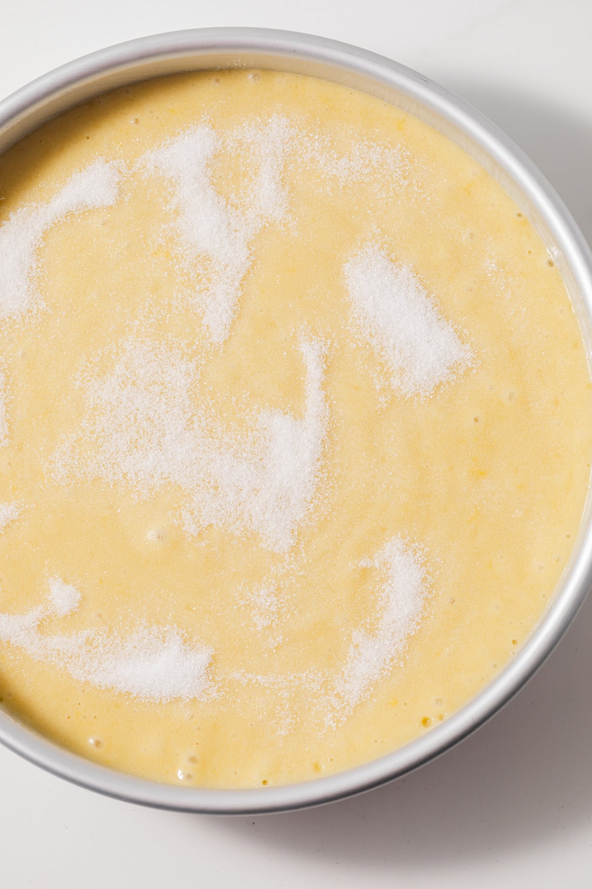 Cake batter sprinkled with sugar in cake pan.