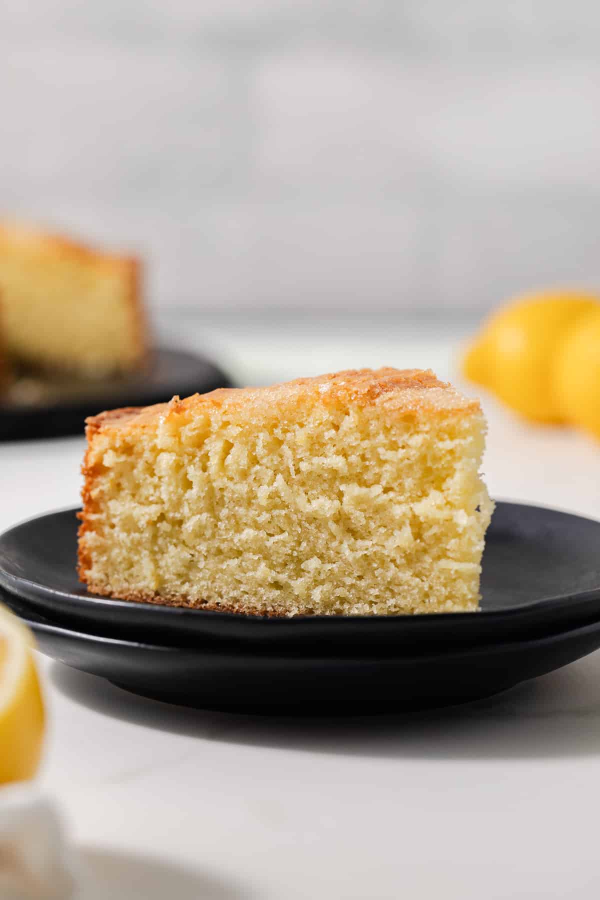 Side view of slice of lemon olive oil cake on plate.
