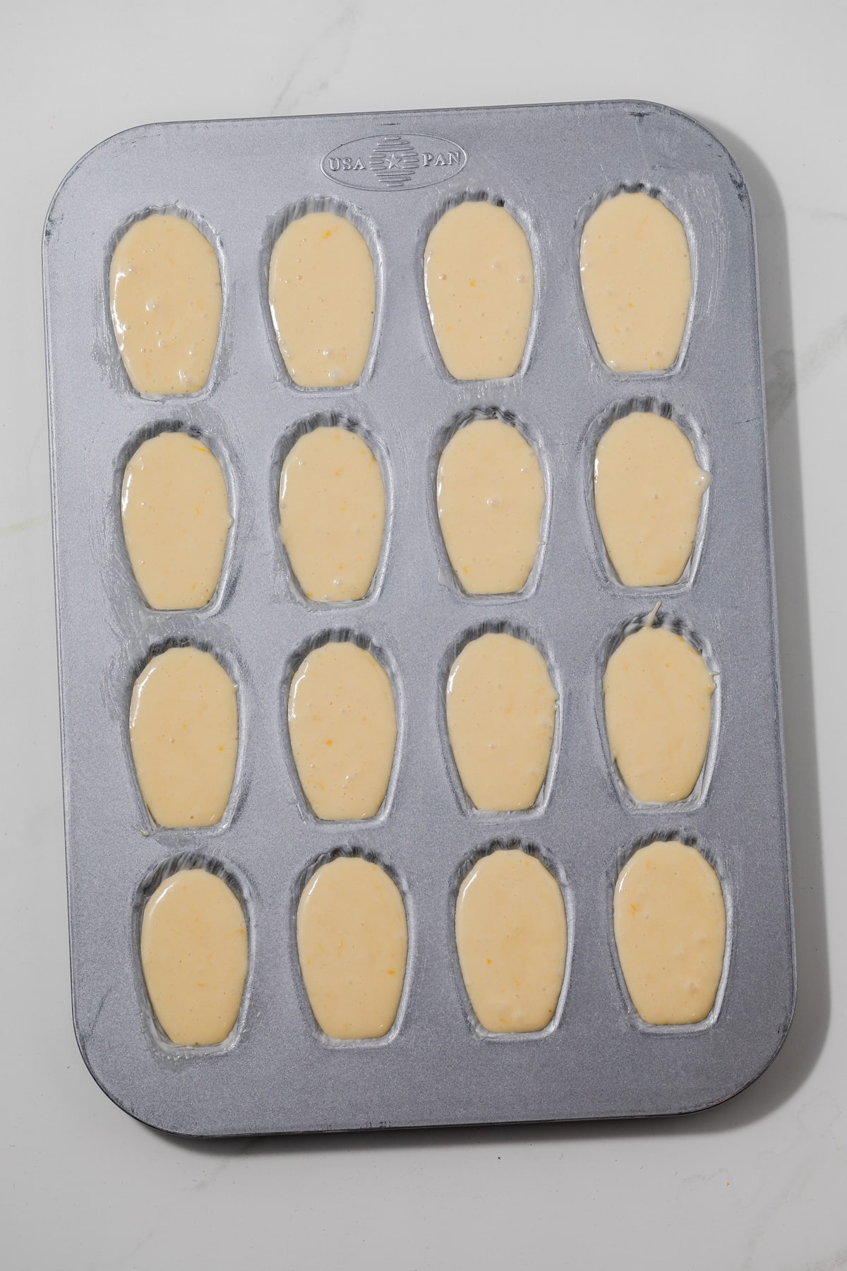 Madeleine batter in baking pan.