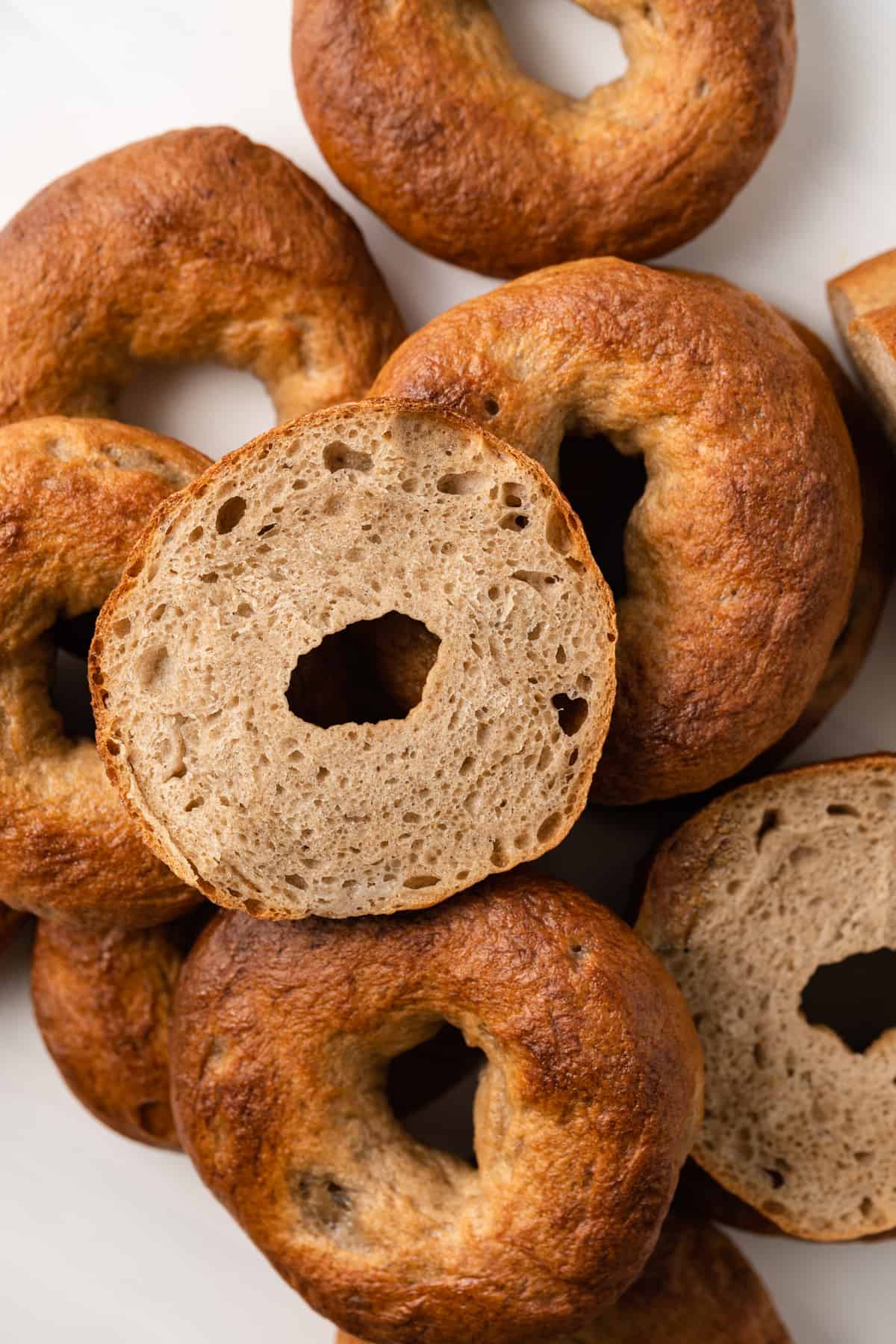 Maple Cinnamon Bagels in pile, with one bagel sliced in half