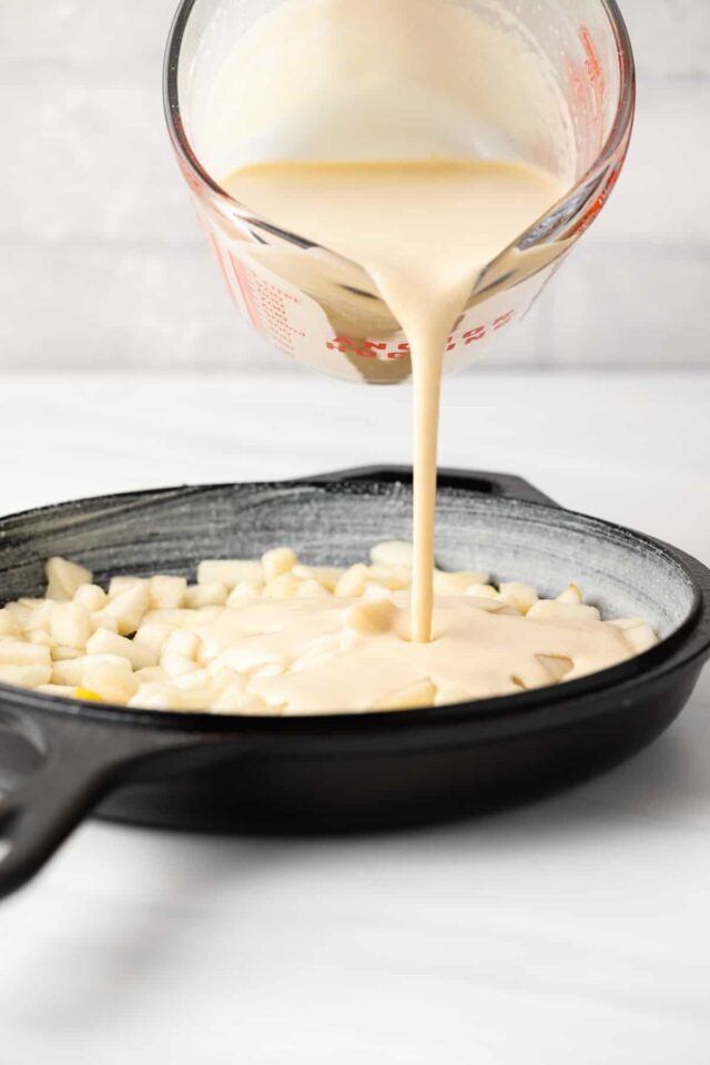 Clafoutis filling being poured over pieces of pears