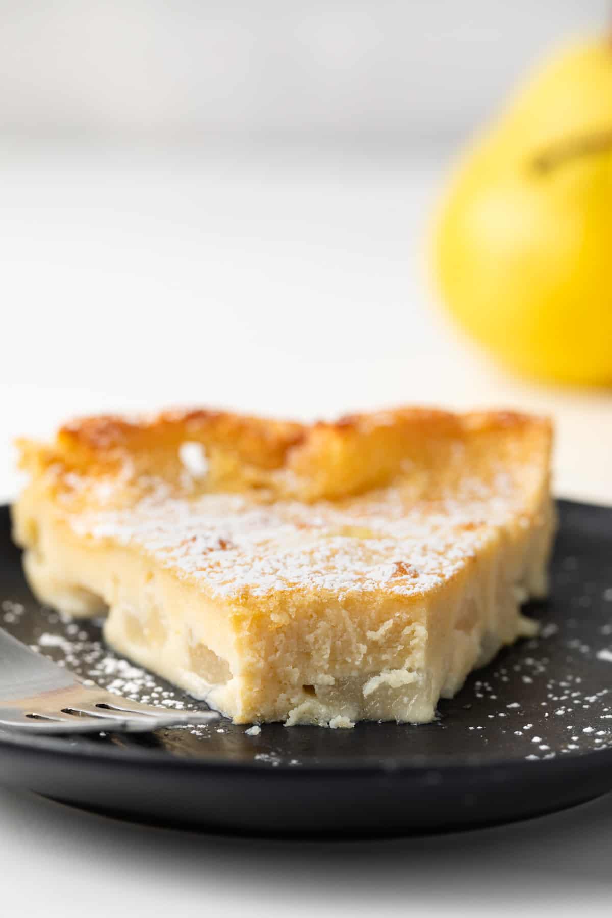 Slice of maple pear clafoutis on a plate with bite taken out.