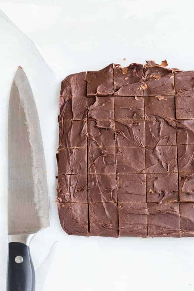 Mexican hot chocolate fudge sliced on white parchment paper with a knife next to it.