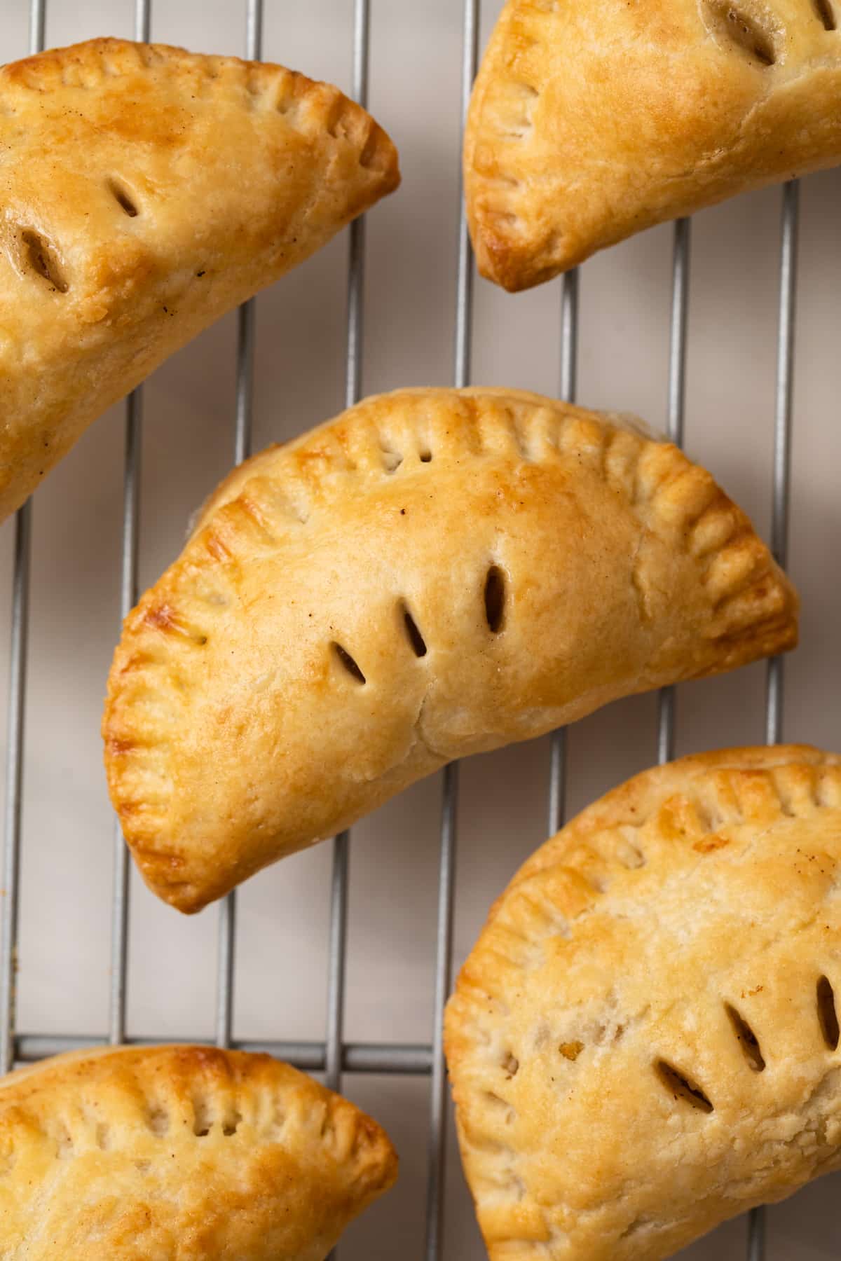 Close up of mini apple pies on a wire rack.