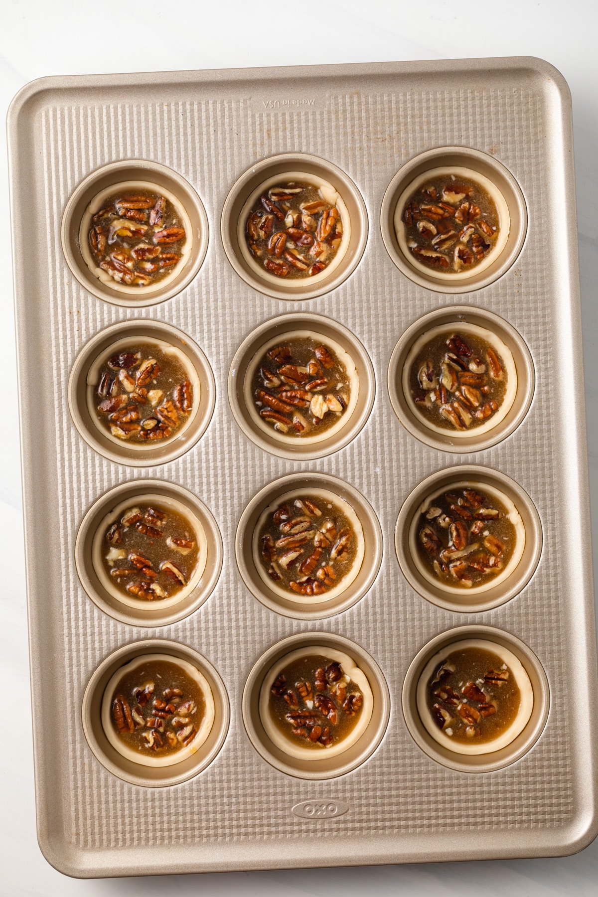 Pecan pie filling in pie crusts in muffin pan.