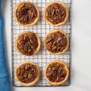 Overhead of mini pecan pies on wire rack.