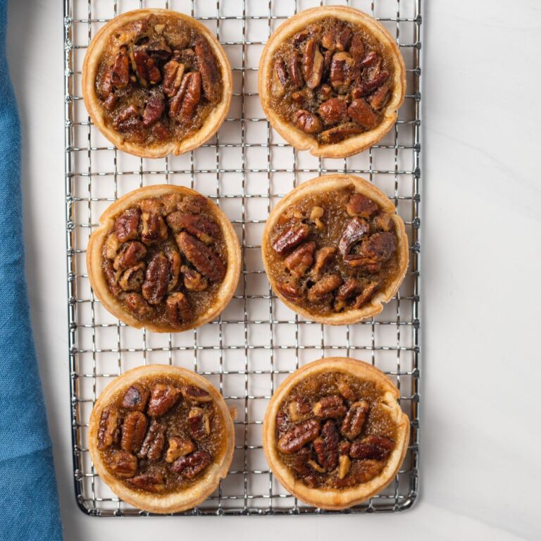 Overhead of mini pecan pies on wire rack.