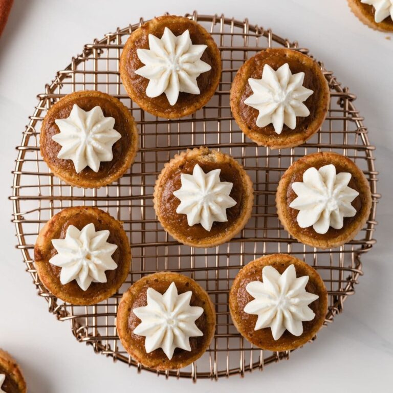 overhead of mini pumpkin pies with whipped cream set on a round wire rack