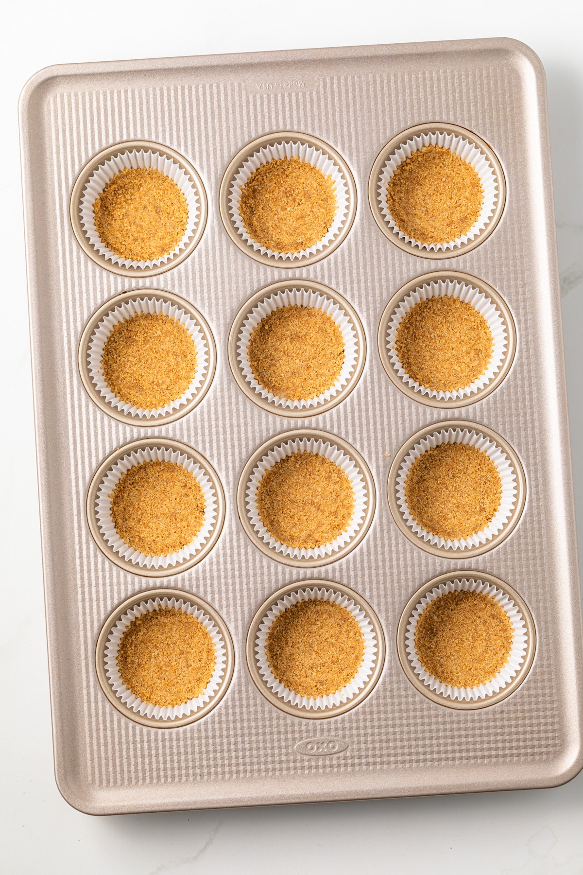 Muffin pan filled with graham cracker crusts.