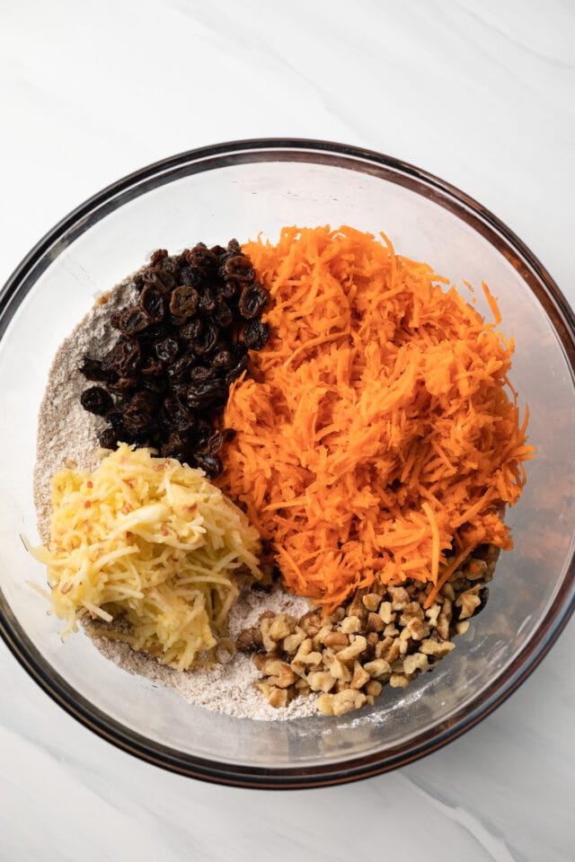 Shredded carrot, raisins, nuts, and crushed pineapple in a bowl.