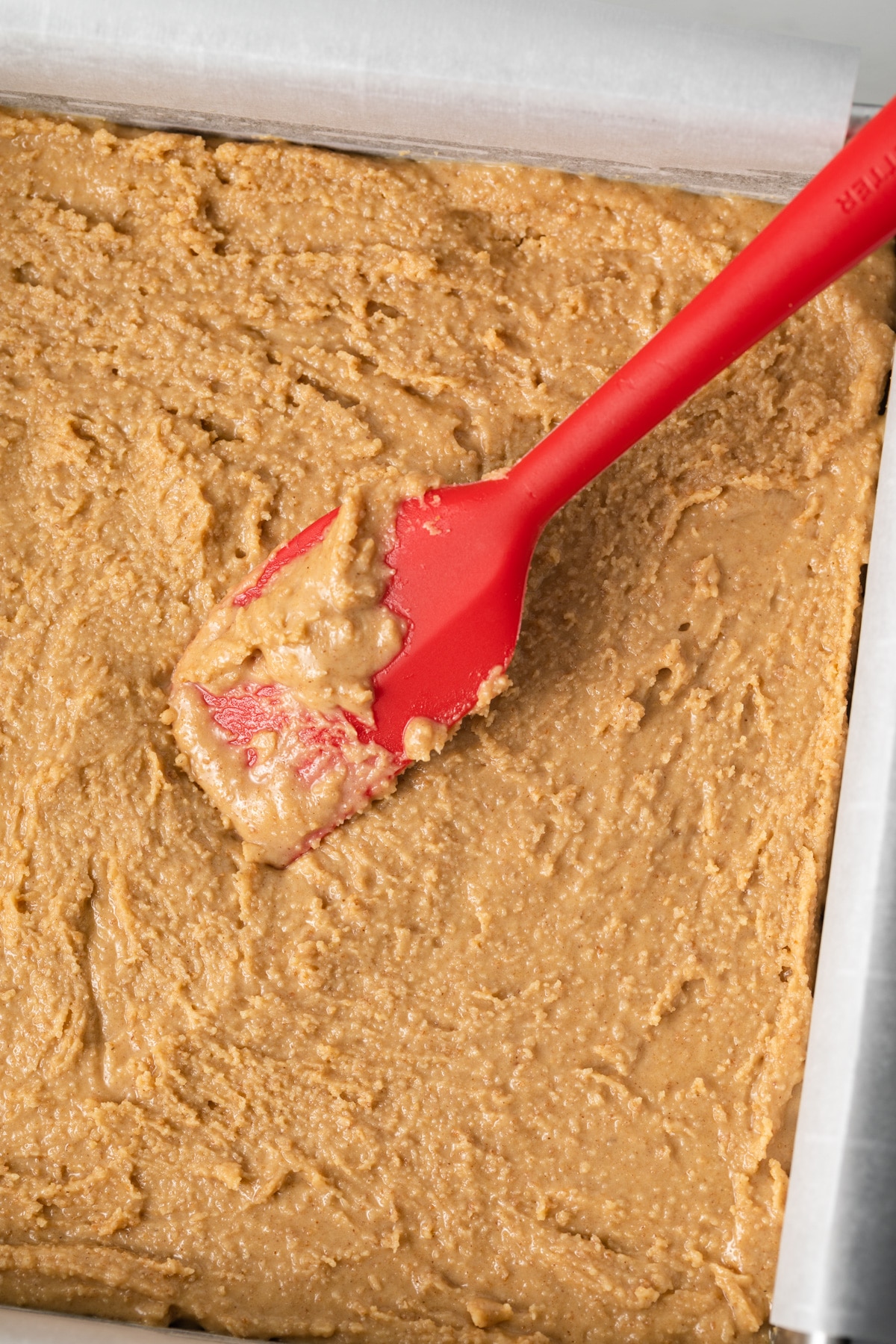 Peanut butter bar dough in pan with parchment paper.