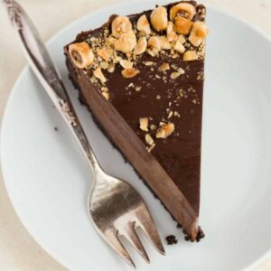 A slice of no bake Nutella cheesecake on a white plate with a fork next to it.