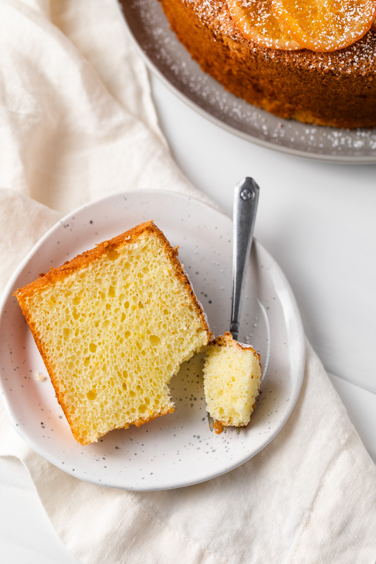 slice of orange chiffon cake with fork taking a bite out