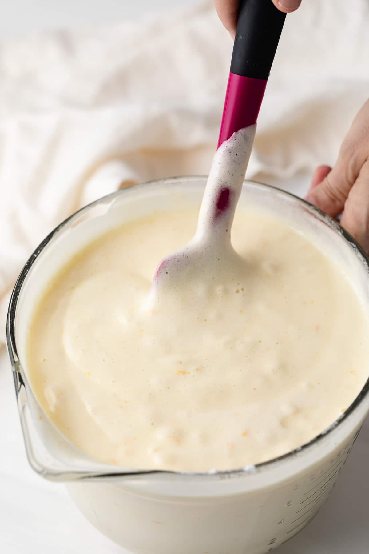 orange chiffon cake batter in glass bowl with pink spatula
