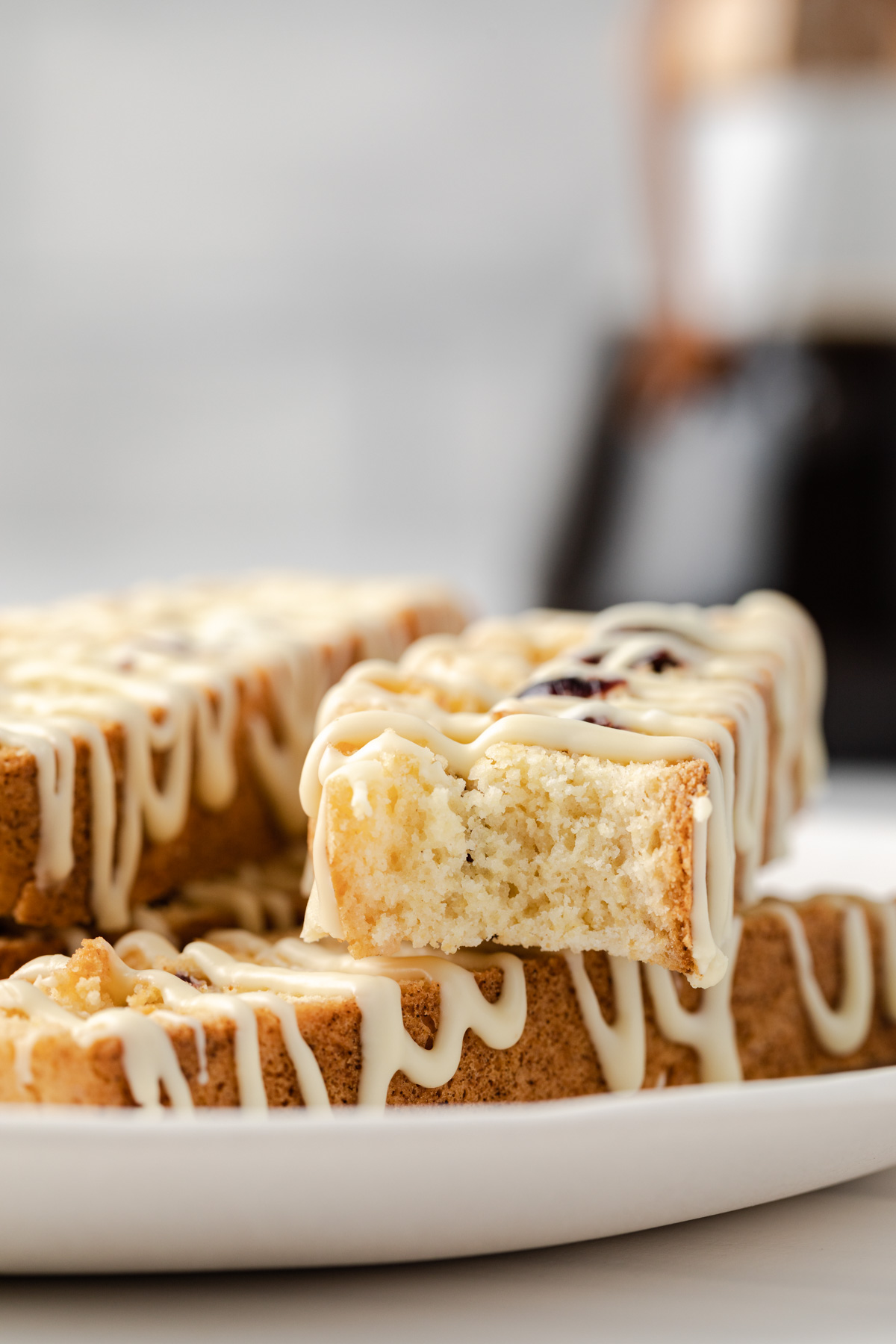 Orange cranberry biscotti on a plate, the top one with a bite missing