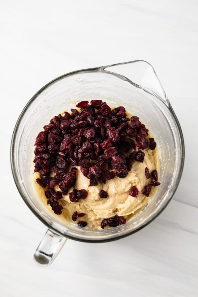 Cranberries added to a bowl with biscotti dough