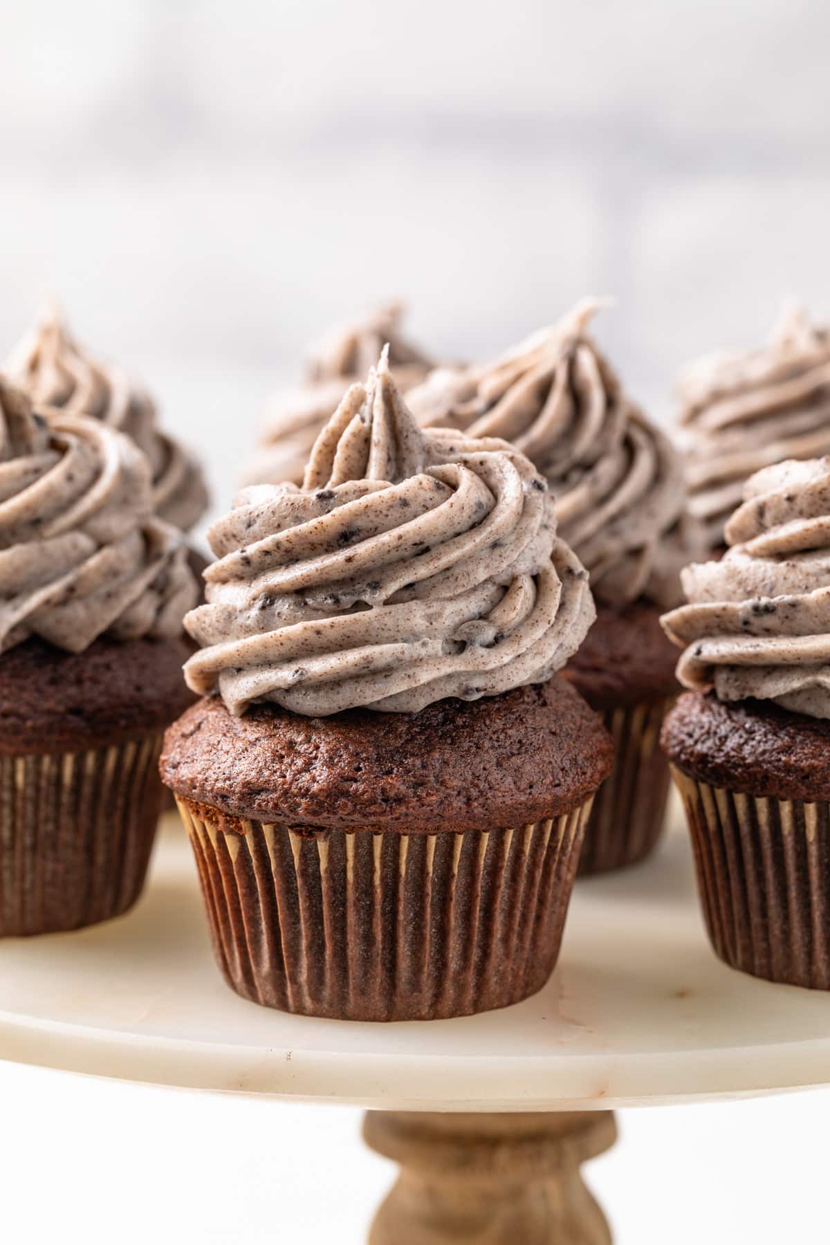 Oreo frosting over chocolate cupcakes on a cake stand.