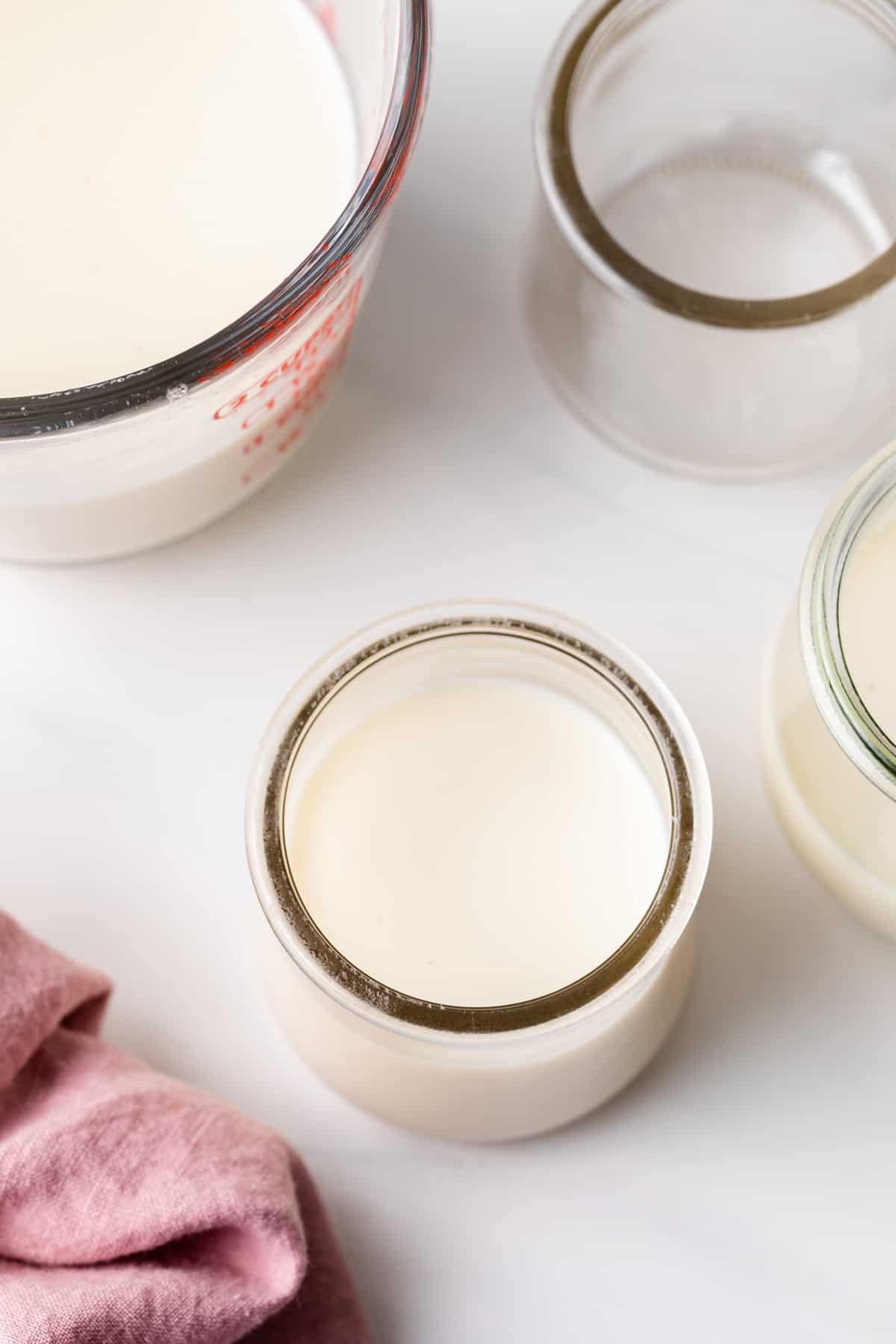 cooked custard in a glass jar and liquid measuring cup