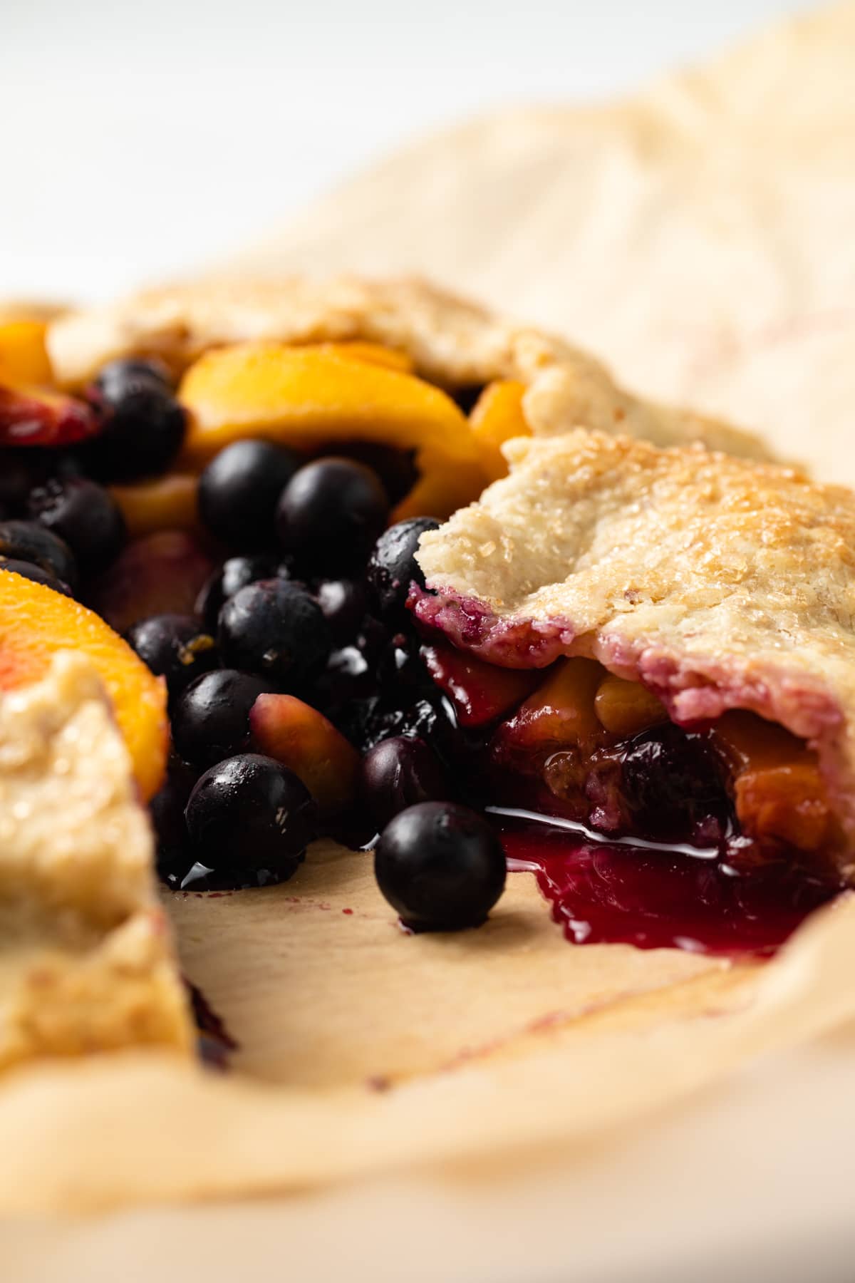 Side view of peach blueberry galette with slice taken out.