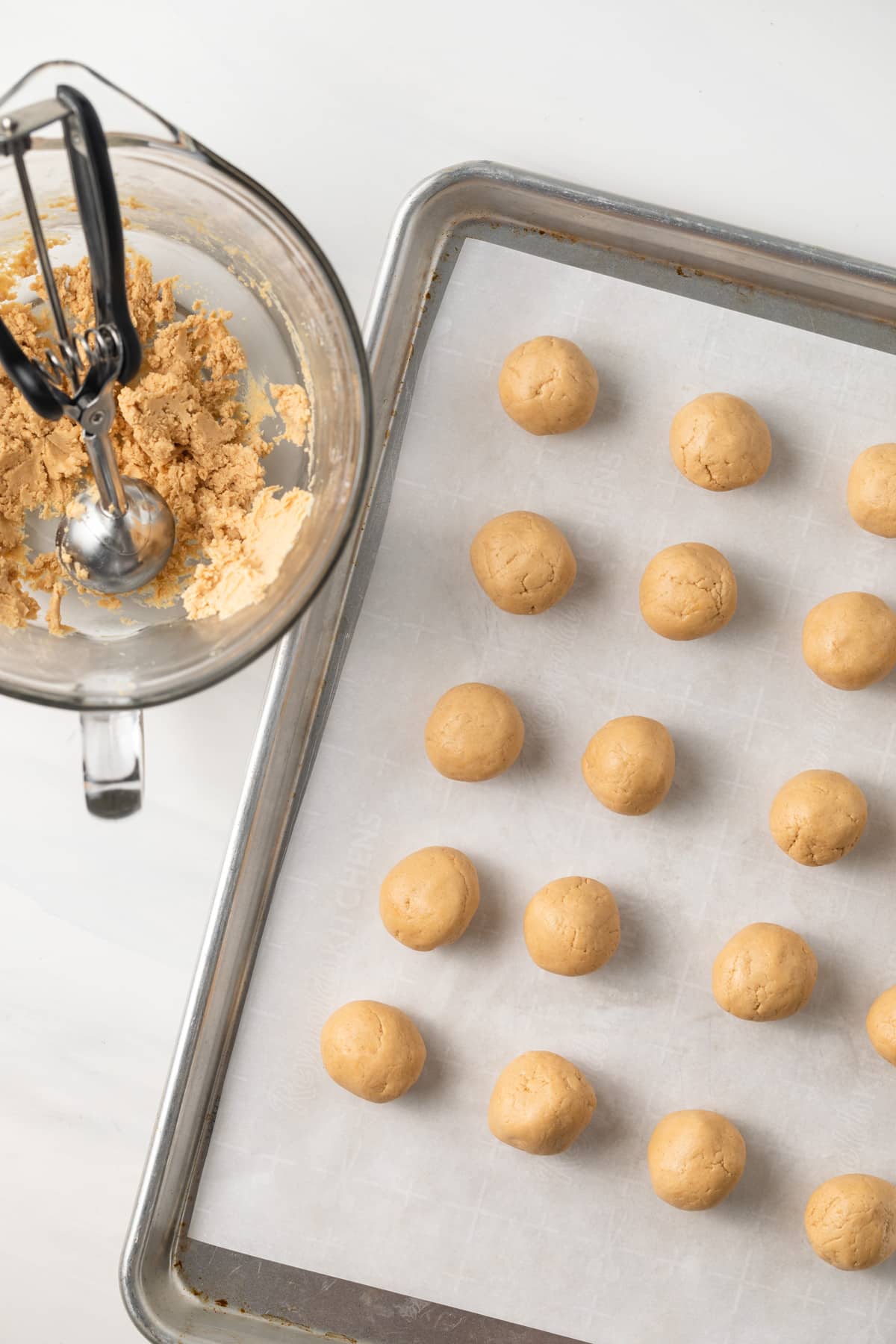 Rolled peanut butter balls on baking sheet.