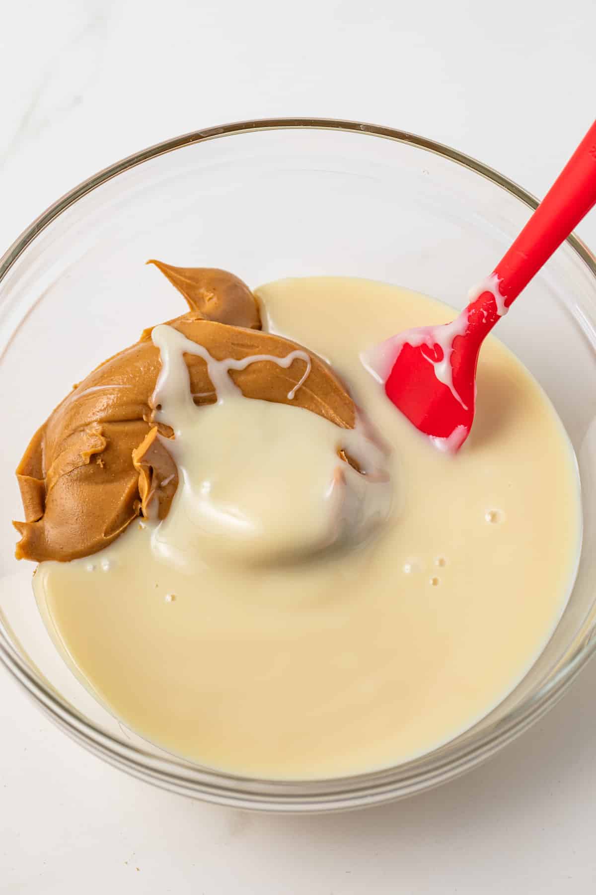 Peanut butter and condensed milk in a glass bowl.
