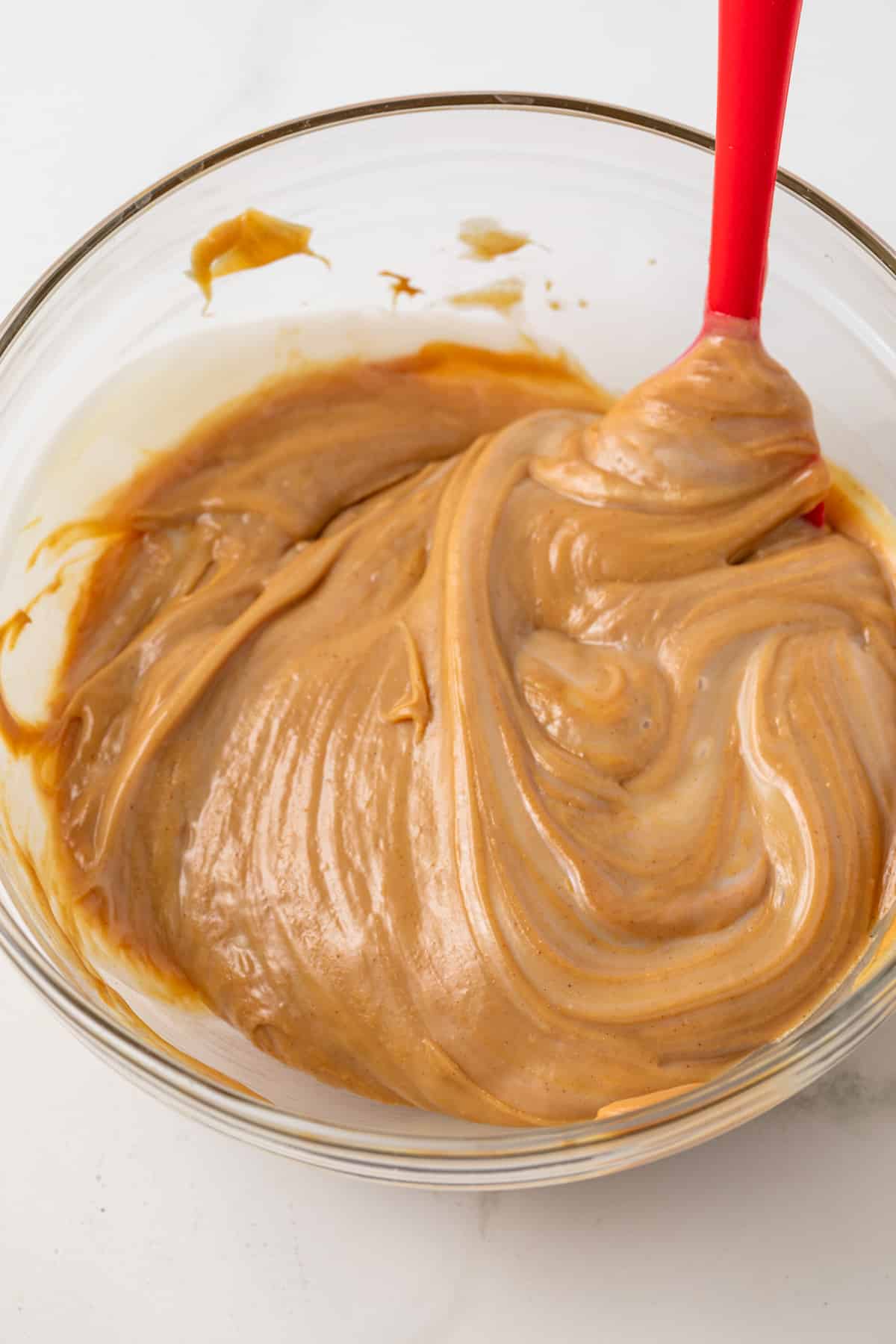 Peanut butter and condensed milk mixed in a glass bowl.
