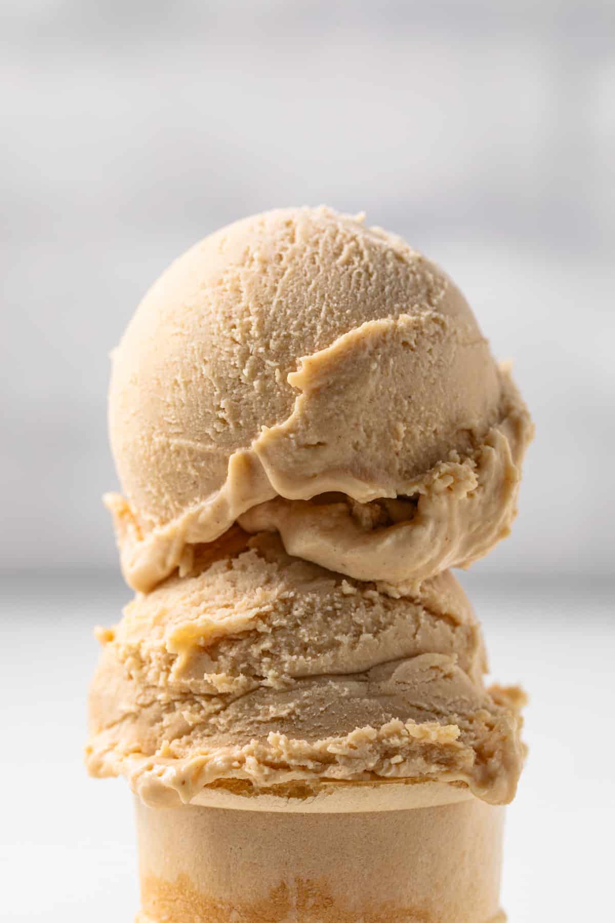 Two scoops of peanut butter ice cream on a cone.