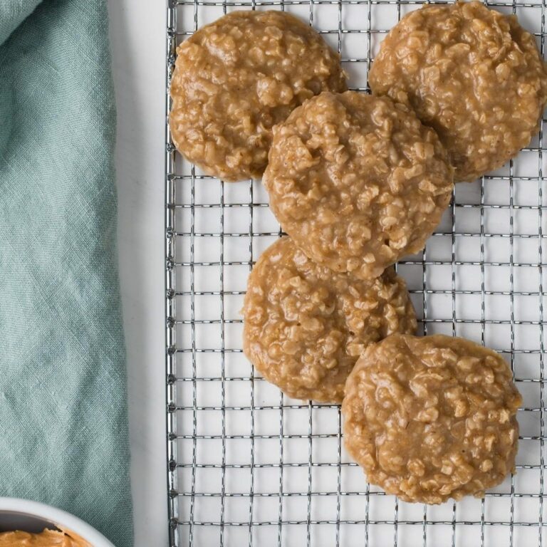 overhead view of peanut butter no bake cookies scattered on a wire rack next to a bowl of peanut butter and light blue-green cloth