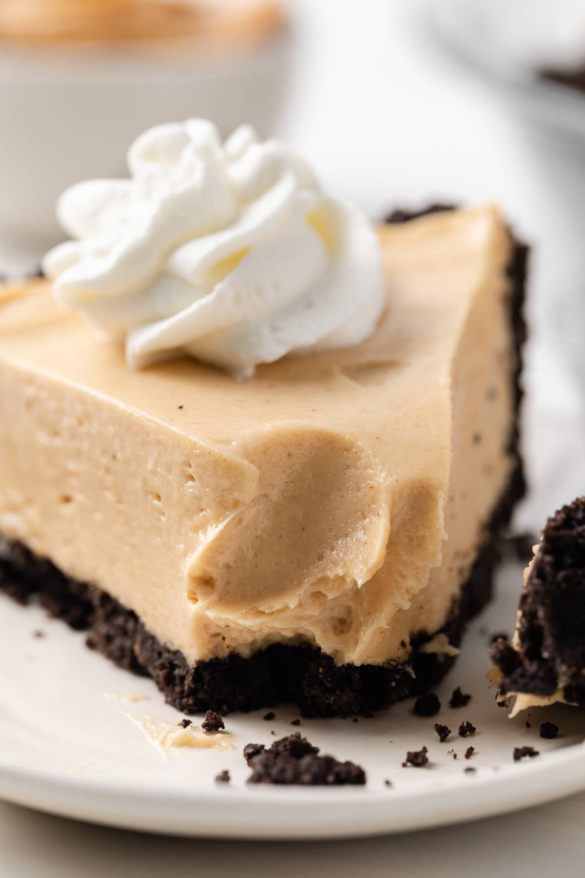 close up of slice of peanut butter pie with oreo crust and whipped cream swirl with a bite taken out