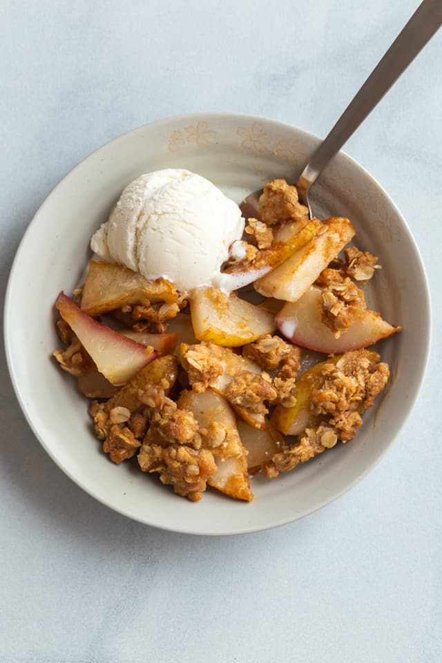 overhead view of pear crisp in a bowl with a scoop of ice cream