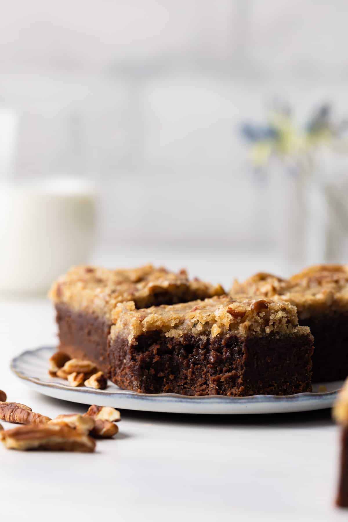 3 candied pecan brownies on a plate with a bite missing