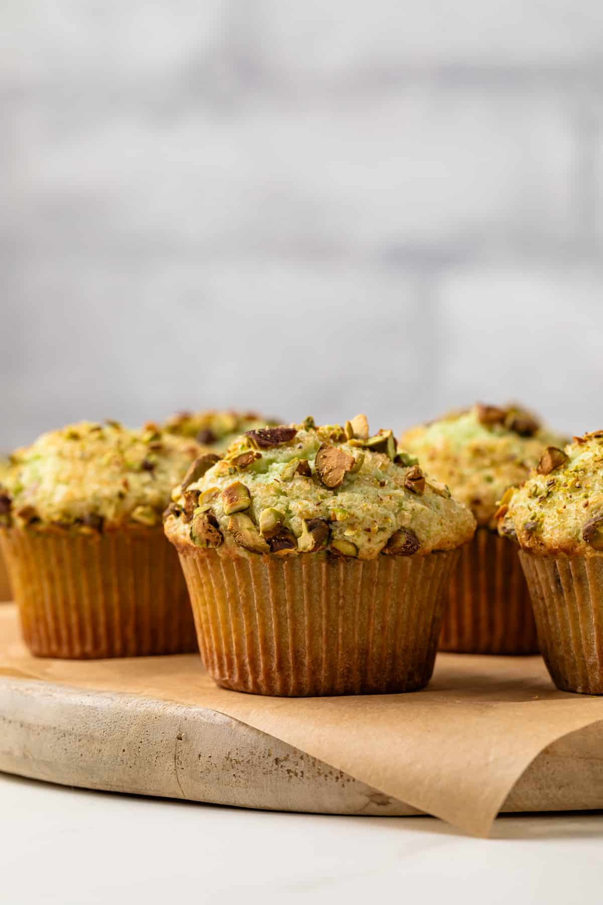 Bakery style pistachio muffins on a serving platter.